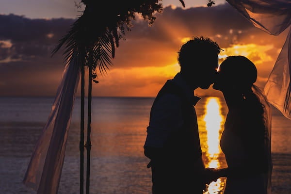 夕陽の海辺でキスを新郎新婦